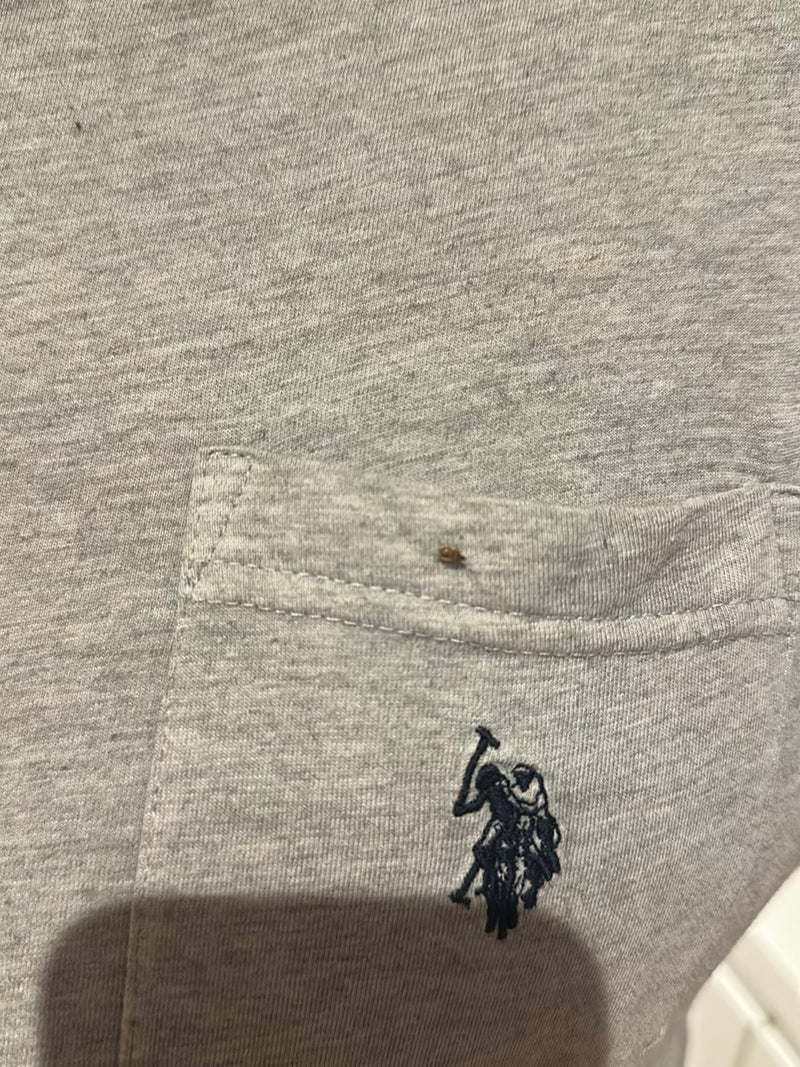 Una piccola cimice dei letti è seduta su un tessuto tessile grigio con una tasca. L'insetto è molto piccolo e difficilmente riconoscibile.