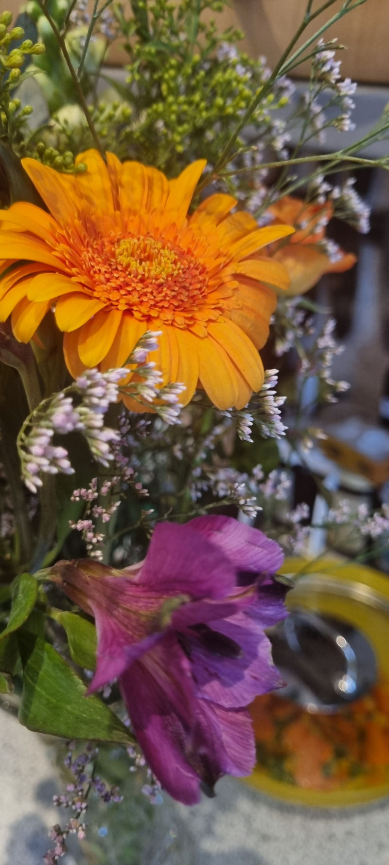 Si vede una gerbera arancione brillante come parte di un bouquet colorato. I petali caratteristici e l'infiorescenza a capolino sono chiaramente visibili.